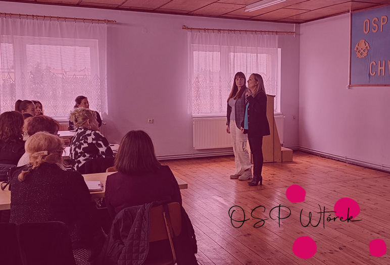 Zdjęcie prezentuje dwie osoby mówiące do grupy osób, które siedzą w dużej przestrzeni.